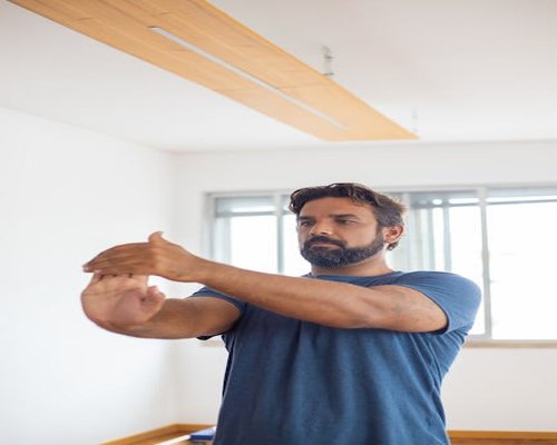 Person doing light arm stretches near an office window